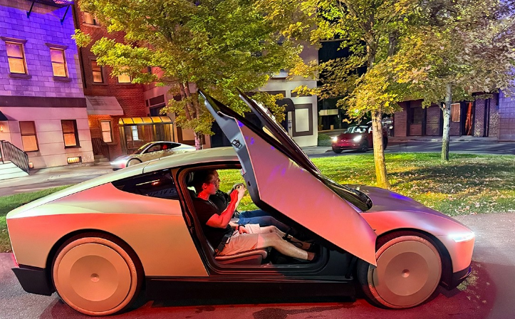 Futurisztikus elektromos sportautó felnyíló szárnyajtóval egy éjszakai utcán